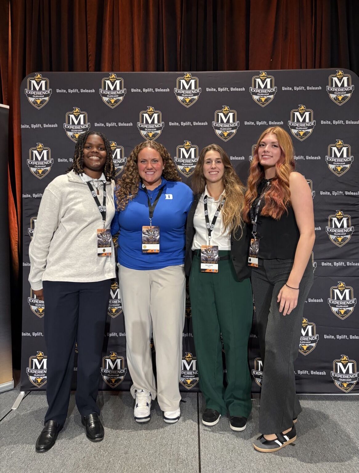 Four attendees in front of The McLendon Experience backdrop