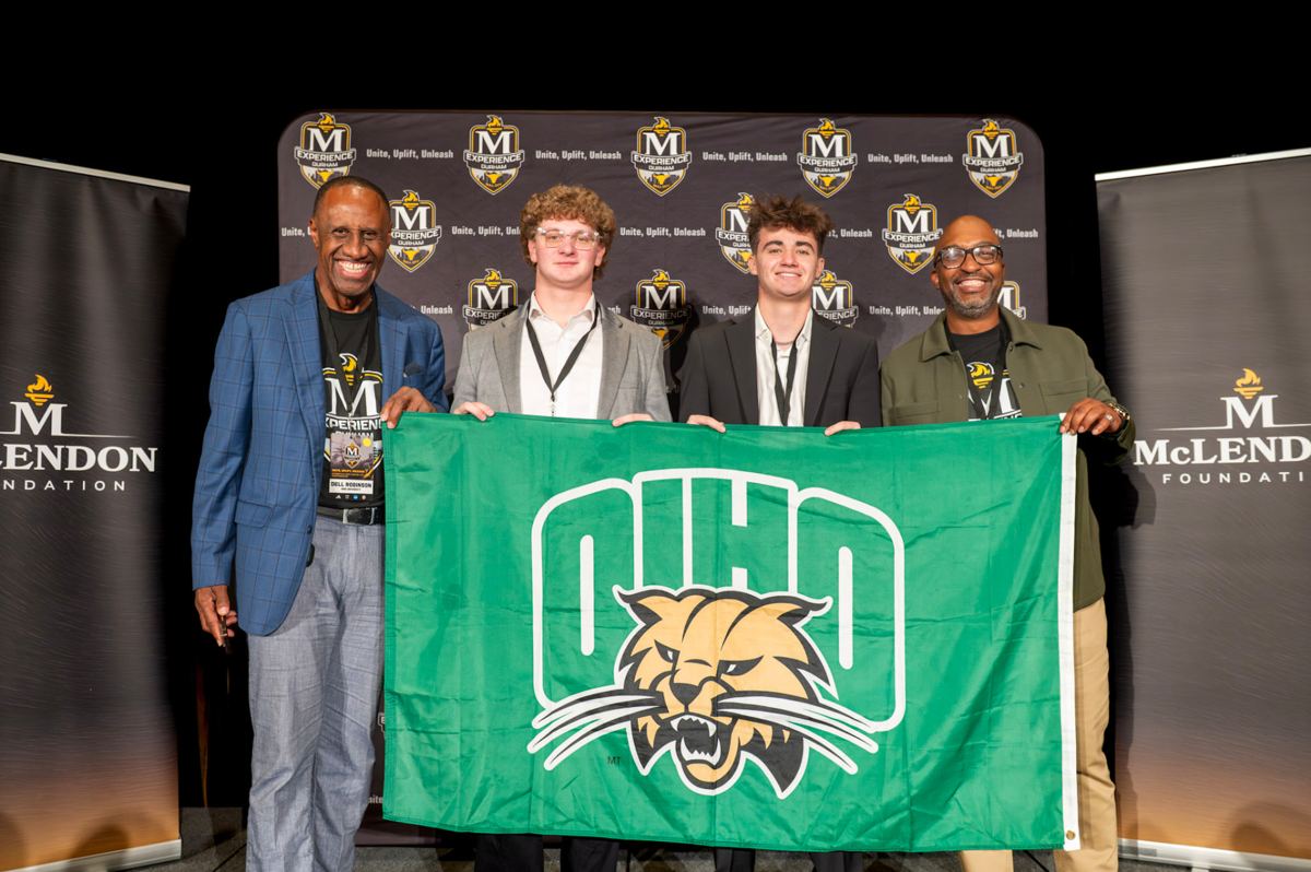 Students recognized on stage with their university flag at The McLendon Experience