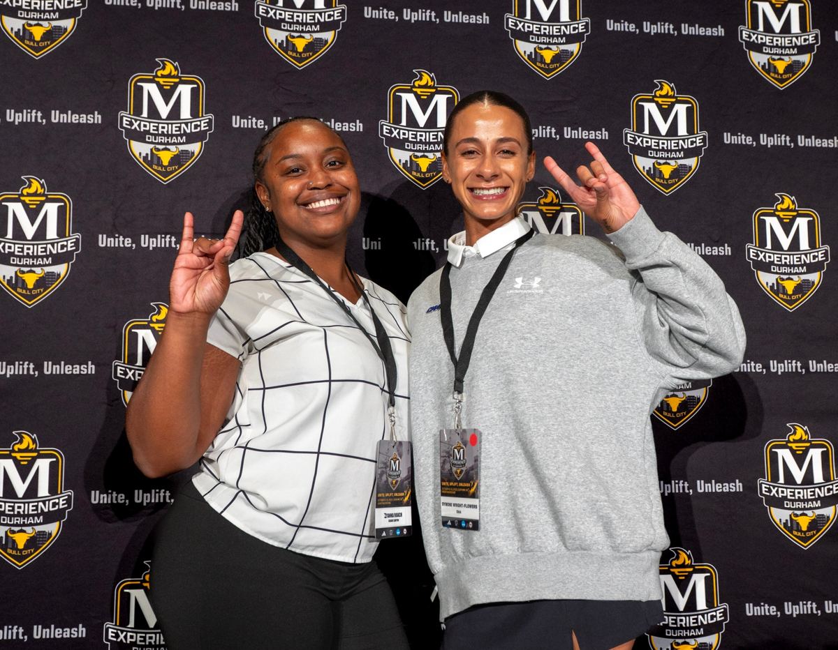 Two McLendon Foundation Torchbearers celebrating in front of The McLendon Experience backdrop